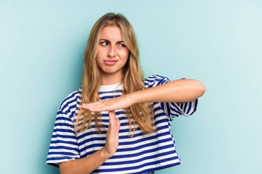 Mavi arka planda izole edilmiş beyaz tenli genç bir kadın bir mola hareketi gösteriyor..