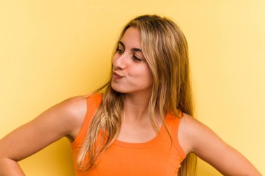 Sarışın, sarı arka planda izole genç bir kadın hedeflerine ve amaçlarına ulaşma hayali kuruyor.