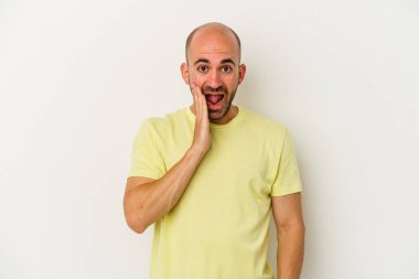 Beyaz arka planda izole olmuş genç kel adam yüksek sesle bağırıyor, gözleri açık ve elleri gergin tutuyor..
