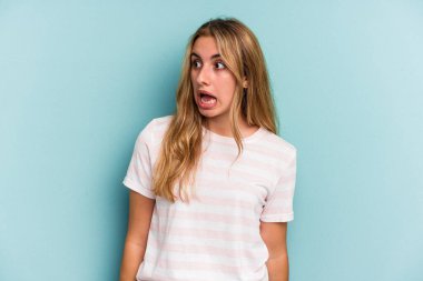 Mavi arka planda izole edilmiş beyaz bir kadın gördüğü bir şey yüzünden şoka uğruyor..