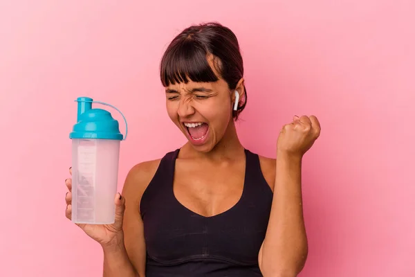 勝利の後に拳を上げピンクの背景に隔離されたタンパク質シェイクを飲む若い混合人種の女性 勝者の概念 — ストック写真