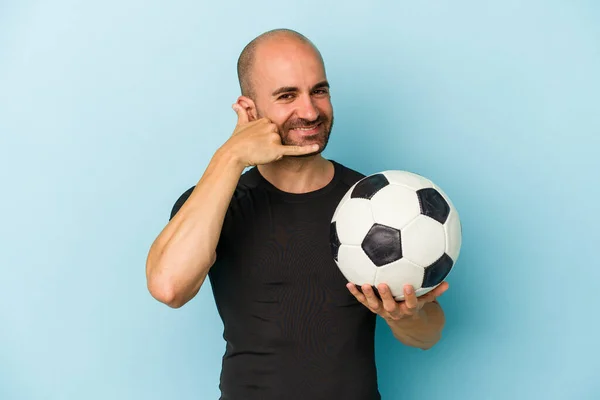 年轻的商人秃头男子在蓝色背景下踢足球 用手指打手机手势 — 图库照片