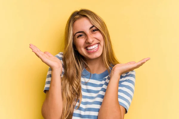 Young Caucasian Blonde Woman Isolated Yellow Background Makes Scale Arms — Stock Photo, Image