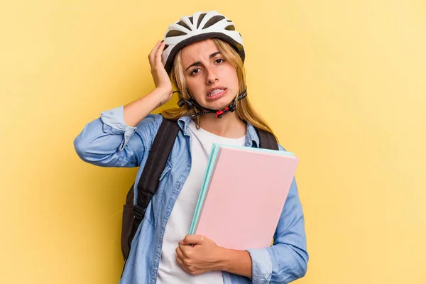 黄色の背景に隔離された自転車のヘルメットを身に着けている若い白人学生の女性はショックを受けて 彼女は重要な会議を覚えています — ストック写真