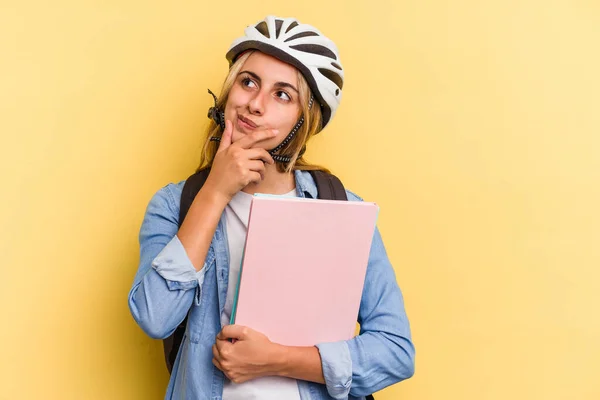 자전거 헬멧을 배경에 고립된 자전거를 코카서스 여학생은 의심스럽고 회의적 표정으로 — 스톡 사진