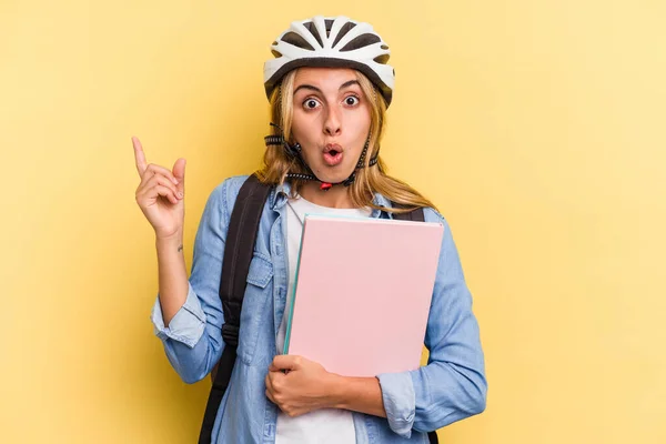 若いですCaucasian学生女性身に着けていますAバイクヘルメット隔離上の黄色の背景を指す側 — ストック写真