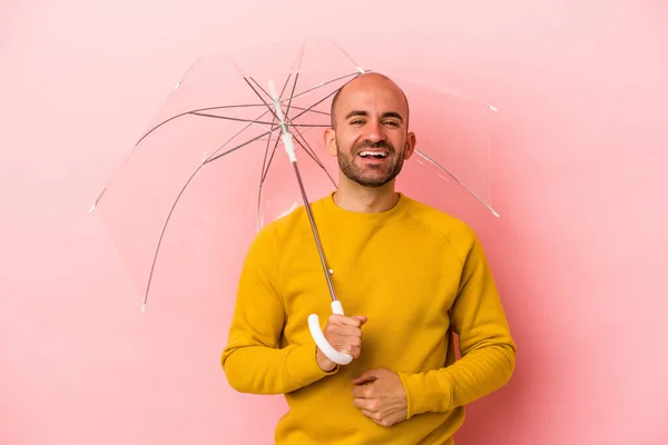 年轻的高加索秃头男人拿着雨伞 与粉色背景隔离 玩得很开心 — 图库照片