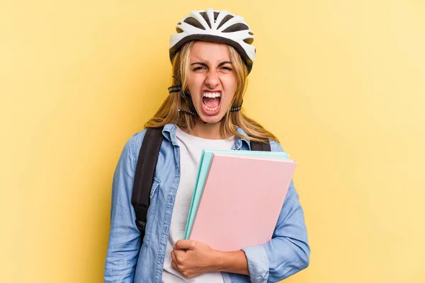 若いですCaucasian学生女性身に着けていますAバイクヘルメット隔離上の黄色の背景悲鳴非常に怒っていると積極 — ストック写真