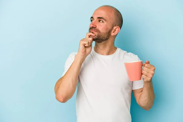 Joven Calvo Sosteniendo Una Taza Aislada Sobre Fondo Azul Mirando — Foto de Stock