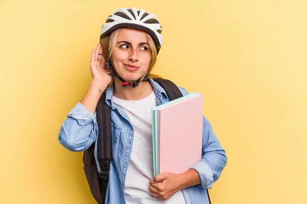 若いですCaucasian学生女性身に着けていますAバイクヘルメット隔離された上に黄色の背景に聞こうとしているゴシップ — ストック写真