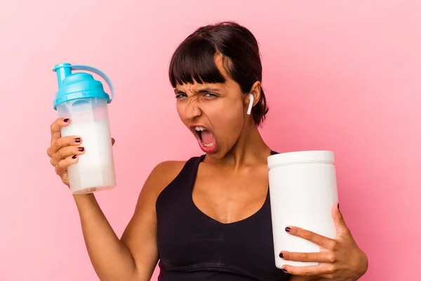 ピンクの背景に隔離されたタンパク質シェイクを飲む若い混合人種の女性 — ストック写真