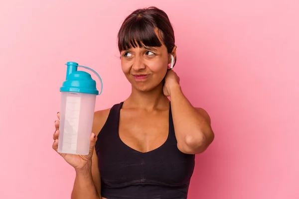 若い混合人種の女性は タンパク質を飲んで頭の後ろに触れるピンクの背景に隔離された振る 思考と選択をする — ストック写真