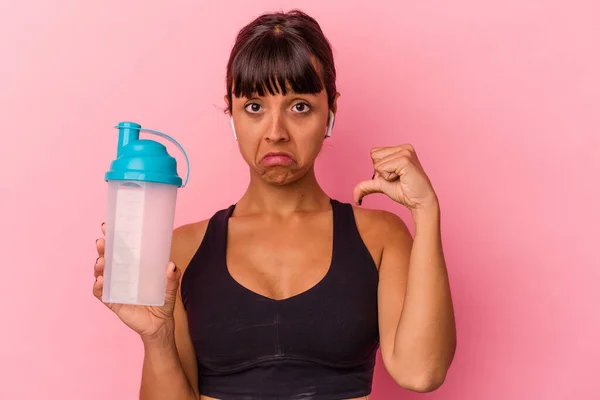 ピンクの背景に単離されたタンパク質シェイクを飲む若い混合人種の女性は誇りと自信を感じています 次の例に従うこと — ストック写真