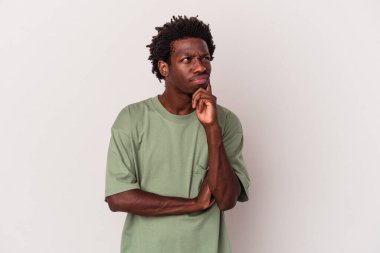 Genç Afrikalı Amerikalı bir adam beyaz arka planda izole edilmiş düşünüyor, yukarı bakıyor, yansıtıyor, düşünüyor, bir fantezi kuruyor..