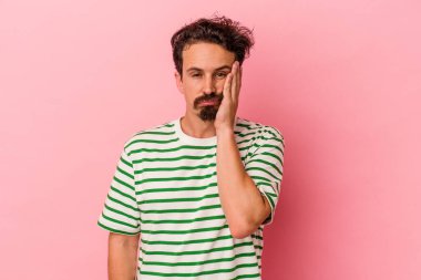 Pembe arka planda izole edilmiş, üzgün ve dalgın hisseden, fotokopi alanına bakan genç beyaz bir adam..