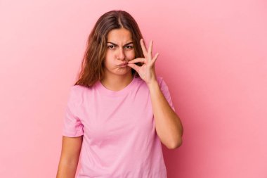 Pembe arka planda izole edilmiş genç beyaz kadın parmakları dudaklarında bir sır saklıyor..