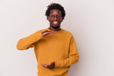 Beyaz arka planda izole edilmiş genç Afrikalı Amerikalı iki eliyle bir şey tutuyor, ürün sunumu..