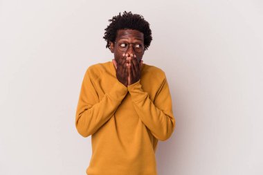 Genç Afrikalı Amerikalı bir adam beyaz arka planda izole edilmiş. Düşünceli bir şekilde bir fotokopi odasına bakıyor. Ağzını eliyle kapatıyor..