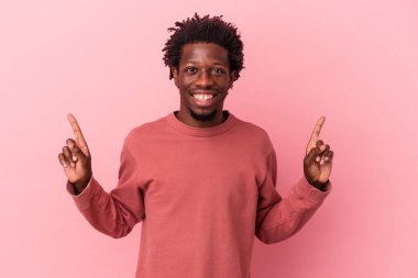 Pembe arka planda izole edilmiş genç Afrikalı Amerikalı iki parmağı da boş bir alan gösteriyor..