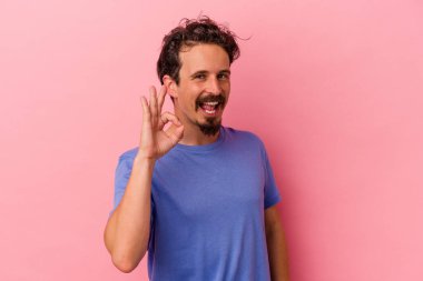 Pembe arka planda izole edilmiş genç beyaz adam neşeli ve kendinden emin, iyi bir hareket gösteriyor..