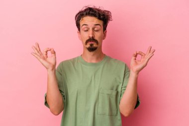 Pembe arka planda izole edilmiş genç beyaz adam sıkı çalışma gününden sonra rahatlıyor. Yoga yapıyor..