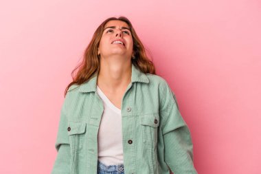 Pembe arka planda izole edilmiş genç beyaz kadın çok kızgın, öfkeli, hayal kırıklığına uğramış.