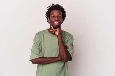 Beyaz arka planda izole edilmiş, mutlu ve kendinden emin gülümseyen, elleriyle çenesine dokunan genç bir Afrikalı Amerikalı..