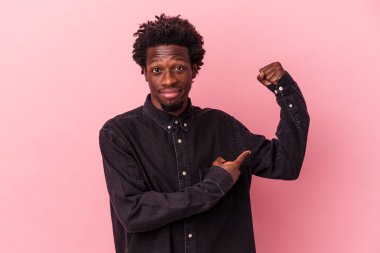Pembe arka planda izole edilmiş genç Afro-Amerikan erkeği güçlü bir hareket sergiliyor, kadınsı gücün sembolü.