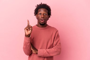 Genç Afrikalı Amerikalı bir adam pembe arka planda izole edilmiş. Harika bir fikri var, yaratıcılık kavramı..