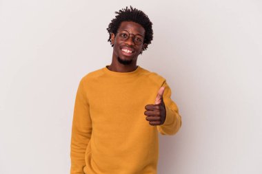 Genç Afrikalı Amerikalı adam beyaz arka planda izole edilmiş gülümsüyor ve başparmağını kaldırıyor.