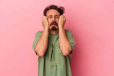 Kafkasyalı genç bir adam pembe arka planda izole edilmiş ağlıyordu, bir şeyden mutsuzdu, acı ve kafa karışıklığı içeriyordu..