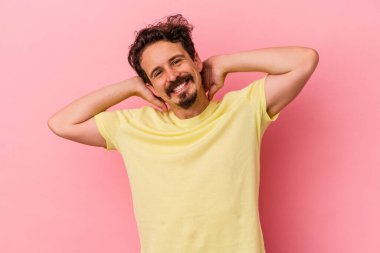 Pembe arka planda izole edilmiş genç beyaz adam kollarını uzatıyor, rahat bir konumda..