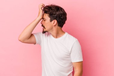 Pembe arka planda izole edilmiş genç beyaz bir adam bir şeyi unutuyor. Alnına avuç içi ve gözlerini kapatarak vuruyor..