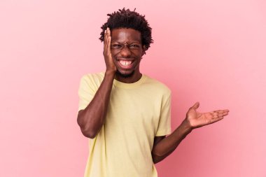 Pembe arka planda izole edilmiş genç Afro-Amerikalı bir adam avuç içinde fotokopi alanı tutuyor, el üstünde tutuyor. Şaşırmış ve mutlu..