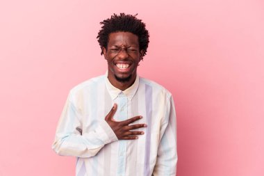 Pembe arka planda izole edilmiş genç Afrikalı Amerikalı adam kahkahalarla gülüyor..