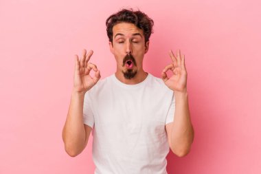 Pembe arka planda izole edilmiş genç beyaz adam sıkı çalışma gününden sonra rahatlıyor. Yoga yapıyor..