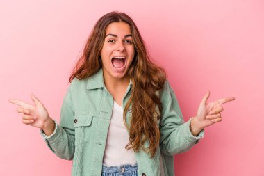 Pembe arka planda izole edilmiş genç beyaz kadın farklı kopya alanlarını gösteriyor, birini seçiyor, parmağıyla gösteriyor..