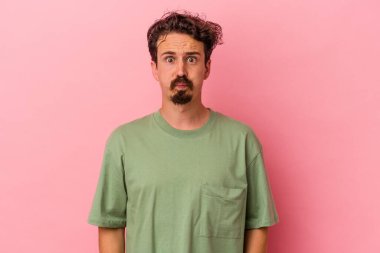 Pembe arka planda izole edilmiş genç beyaz adamın yanakları şişer, yorgun bir ifadesi vardır. Yüz ifadesi kavramı.