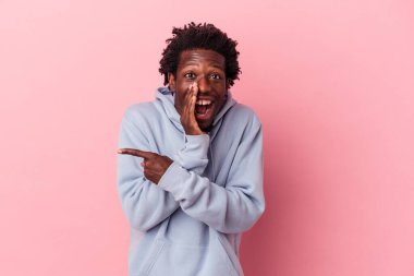 Genç Afrikalı Amerikalı bir adam pembe arka planda izole edilmiş. Dedikodu yapıyor, bir şeyleri bildiriyor..