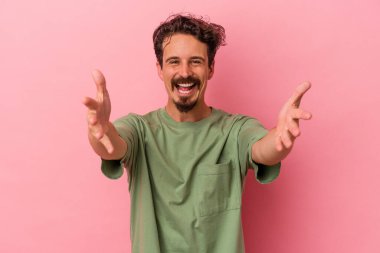 Pembe arka planda izole edilmiş genç beyaz adam kameraya sarıldığı için kendinden emin hissediyor..