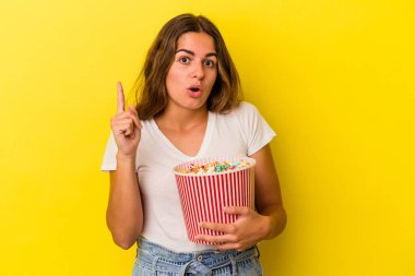 Sarı arka planda izole edilmiş patlamış mısırları tutan beyaz bir kadın. Harika bir fikri var, yaratıcılık kavramı..