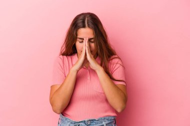 Pembe arka planda izole edilmiş genç beyaz kadın dua ediyor, bağlılık gösteriyor, dindar biri ilahi ilham arıyor..