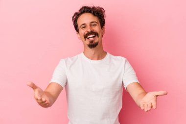 Pembe arka planda izole edilmiş genç beyaz adam hoş bir yüz ifadesi sergiliyor..