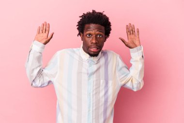 Genç, Afro-Amerikan bir adam pembe arka planda izole edilmiş, yakın bir tehlike nedeniyle şok oluyor.