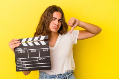 Sarı arka planda el çırpma tahtası tutan beyaz bir kadın hoşlanmadığı bir hareket gösteriyor. Anlaşmazlık konsepti.