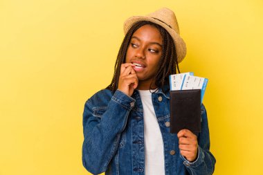 Pasaportu olan genç Afrikalı Amerikalı kadın sarı arka planda izole edilmiş bir şekilde rahat bir şekilde fotokopi odasına bakan bir şeyi düşünüyor..