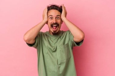 Pembe arka planda izole edilmiş genç beyaz bir adam çığlık atıyor, çok heyecanlı, tutkulu, bir şeyden memnun..