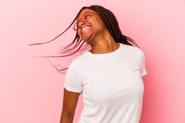 Genç Afrikalı Amerikalı kadın pembe arka planda izole edilmiş dans ediyor ve eğleniyor..