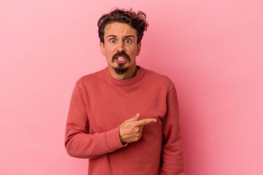 Pembe arka planda izole edilmiş genç beyaz adam yan tarafı gösteriyor.