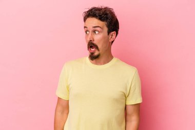 Pembe arka planda izole edilmiş genç beyaz adam gördüğü bir şey yüzünden şoka uğruyor..